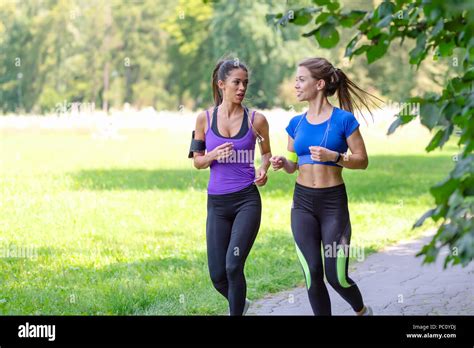 Two Beautiful And Attractive Fitness Girls Are Jogging In The Park On A