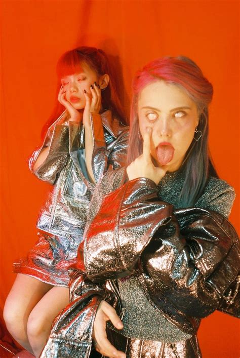 Two Women In Metallic Dresses Posing For The Camera With Their Mouths Open And Tongue Out
