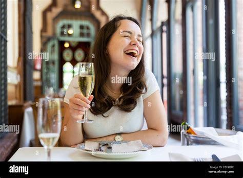 Portrait Of Slightly Drunk Laughing Woman Sitting At Table In