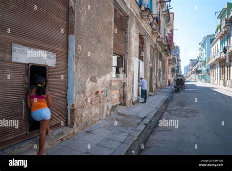 A Cuban Woman Talking To A Neighbor On A Street In A Rundown Section Of
