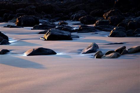 Black Rocks On Sand During Daytime · Free Stock Photo