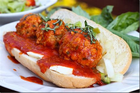 A Meatball Sandwich On A Plate With Lettuce And Tomato Sauce
