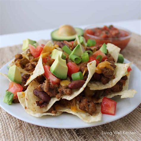These loaded nachos are piled high with chips, beef, beans, cheese, pico de gallo, and avocado. Loaded Nachos | Living Well Kitchen