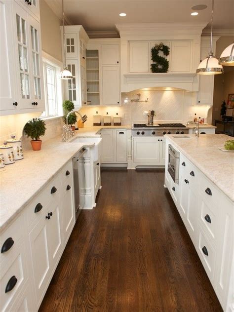 Shaker cabinets have a recessed panel, simple hardware and little decoration — and work with most styles of kitchens. white kitchen, shaker cabinets, hardwood floor, black pulls - Beautiful DIY