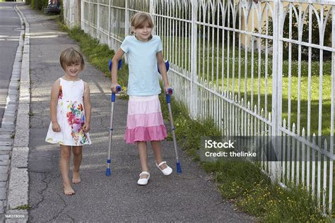 Girl With Crutches Besides Her Little Sister Stock Photo Download