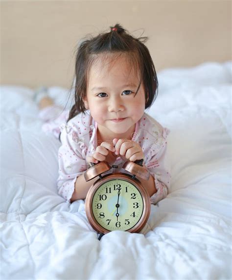 Cute Little Girl With Alarm Clock Lying On Bed Stock Image Image Of