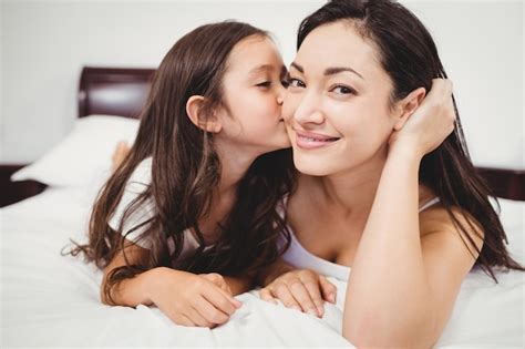 Premium Photo Cute Daughter Kissing Mother On Bed At Home