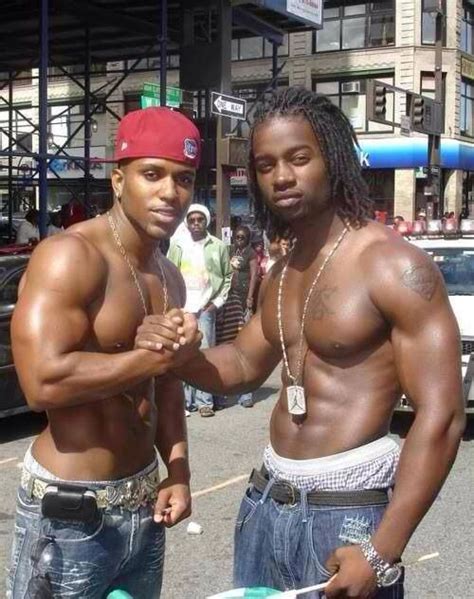 Two Men Standing Next To Each Other In The Street With No Shirts On And One Is Holding A Skateboard
