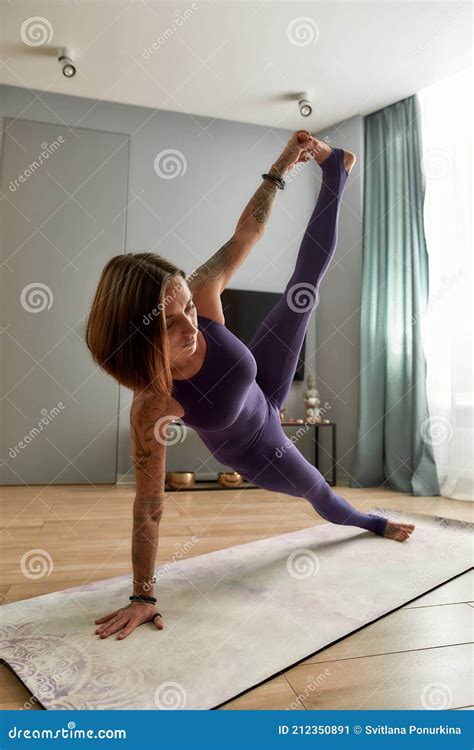 Flexible Young Woman In Bodysuit Stretching Her Body Doing Full Side Plank Yoga Pose On A Mat