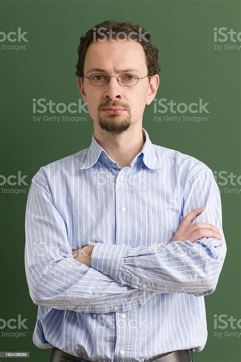 Serious Teacher With Arms Crossed At Blackboard Stock Photo Download