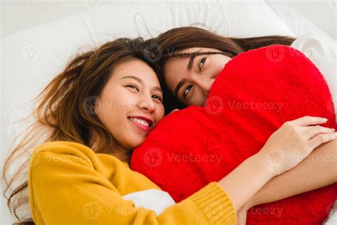 hermosas mujeres asiáticas jóvenes lesbianas lgbt pareja feliz sentada en la cama abrazándose y