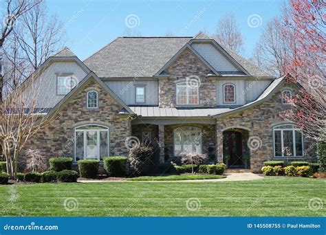 Suburban House With Stone Exterior And Green Lawn In An Affluent