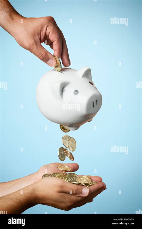 Hand Putting Coin Into Piggy Bank And Coins Flowing Out Stock Photo Alamy