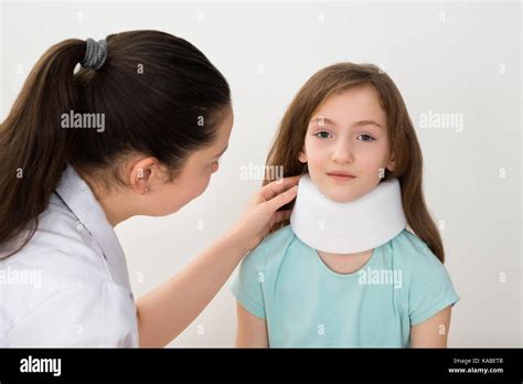 Female Doctor Examining Neck Of Patient Wearing Neck Brace Stock Photo