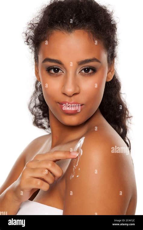 Beauiful Dark Skinned Woman Applying Body Lotion On White Background