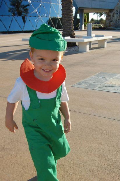 A Young Boy In Green Overalls And A Red Bib