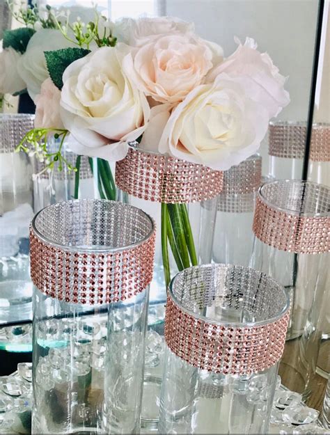 Three Clear Vases Filled With White Flowers On Top Of A Table Next To A Mirror