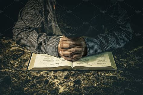 Man Praying To God On An Open Bible High Quality Stock Photos