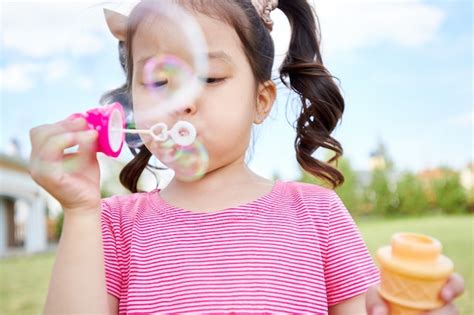 Premium Photo Cute Asian Girl Blowing Bubbles Outdoors