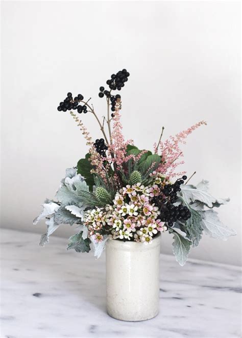 A White Vase Filled With Lots Of Flowers On Top Of A Marble Counter