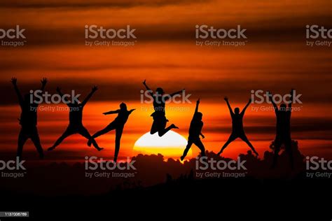 Group Of Happy People Jumping In The Sea At Sunset Concept About Having