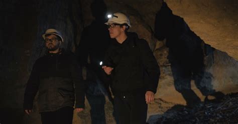 Two Speleologists With Flashlight Exploring The Cave With Fear In