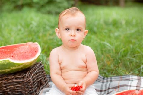 Premium Photo Baby Girl Eats Watermelon In Summer Sitting On The Lawn