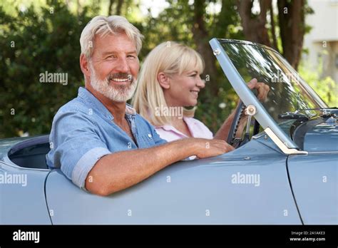 Portrait Of Mature Couple Enjoying Road Trip In Classic Open Top Sports