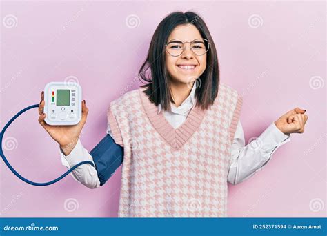 Young Brunette Woman Using Blood Pressure Monitor Screaming Proud