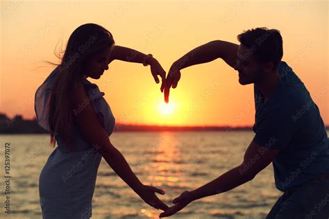 Young Couple In Love Holding Hands In The Shape Of A Large Heart On The