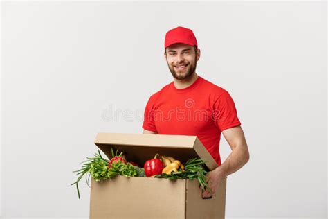 delivery concept handsome caucasian grocery delivery courier man in red uniform with grocery