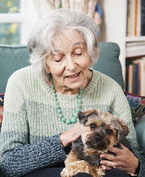 Senior Woman Holding Pet Dog Indoors Living Well Home Medical Equipment