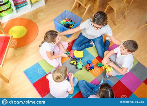 Preschool Teacher Talking To Group Of Children Sitting On A Floor At