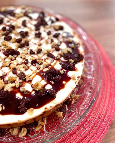 A Cake With Nuts And Cream On Top Sitting On A Glass Plate Next To A