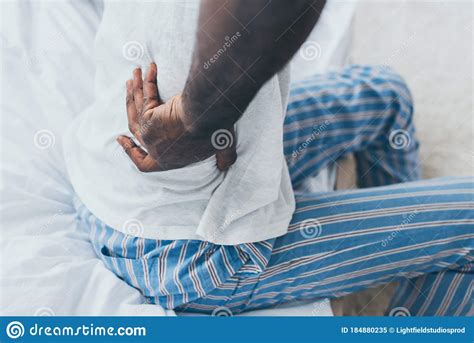 View Of African American Man Suffering From Back Pain In Bedroom Stock