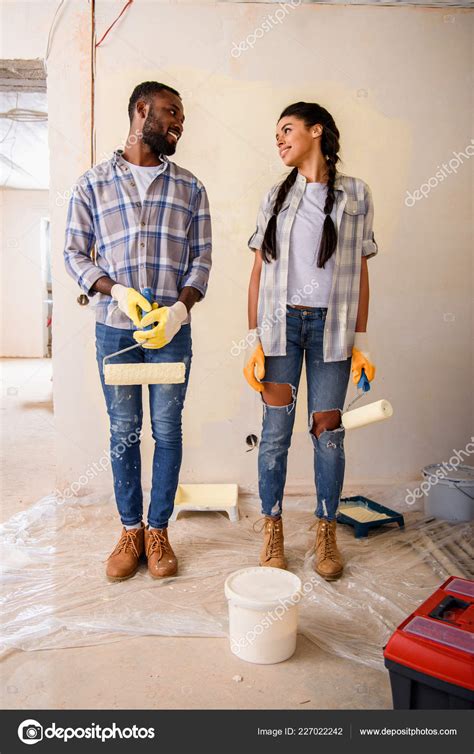 Young Couple Rolling Brushes Looking Each Other While Making Renovation