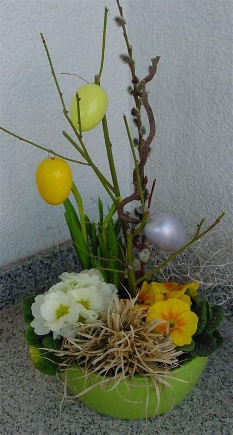 An Arrangement Of Flowers And Plants In A Green Bowl On A Table With