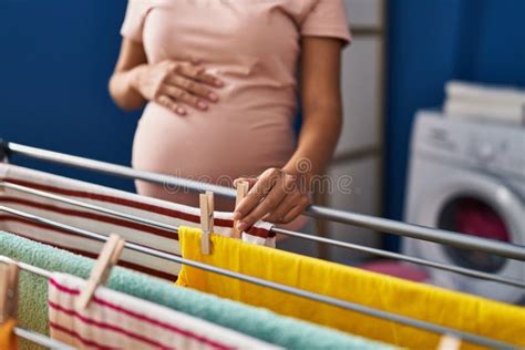 Young Latin Woman Pregnant Hanging Clothes On Clothesline At Laundry