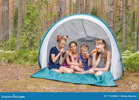Girls Eating Carrots Sitting In Camping Tent During Summer Holidays