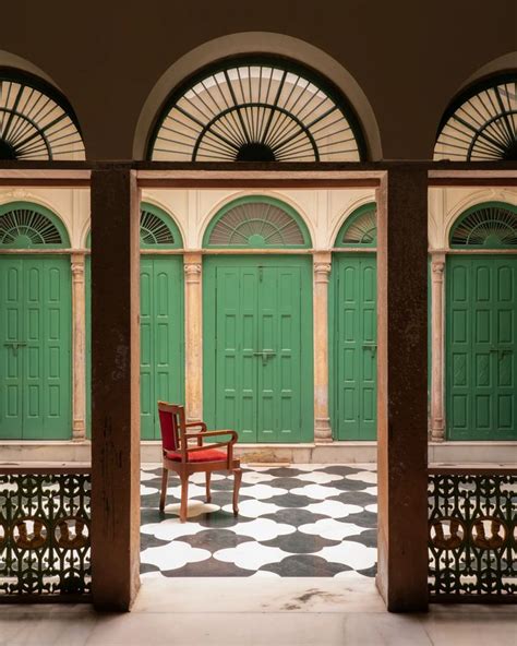 A Red Chair Sitting On Top Of A Checkered Floor In Front Of Green Doors