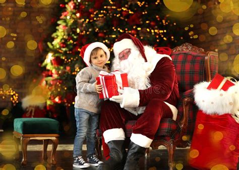 Santa Claus Giving Present To Little Boy Near Christmas Tree Stock