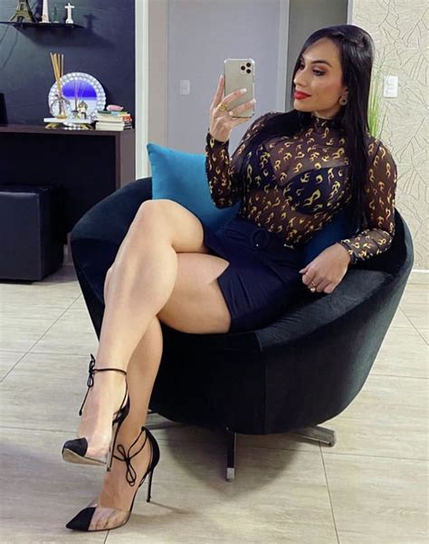 A Woman Sitting In A Chair Taking A Selfie With Her Cell Phone While Wearing High Heels