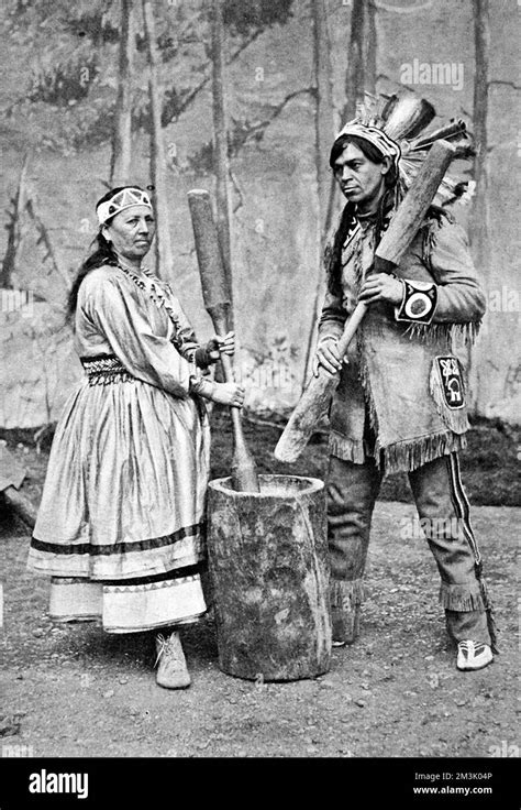 a native american and his wife pounding corn in a large pestle and mortar date 1905 stock