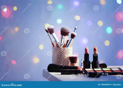 Set Of Decorative Cosmetics With Brushes On Table Against Blurred