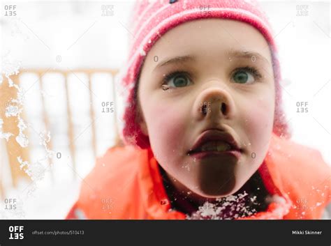 Little Girl Pressing Her Face Against A Window In The Snow Stock Photo