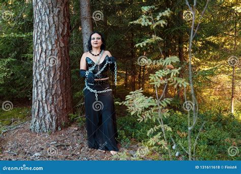 A Young Witch In The Woods Chained To A Tree Halloween Stock Photo