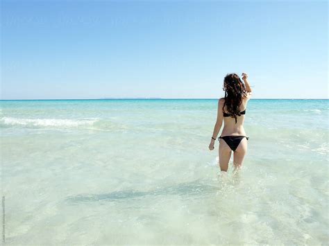 From The Back Woman In A Black Bikini Standing On The Sea Water By