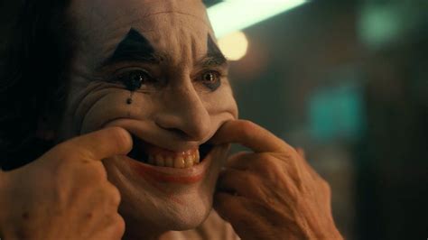 The Joker Is Talking On His Cell Phone With One Hand And Holding It To