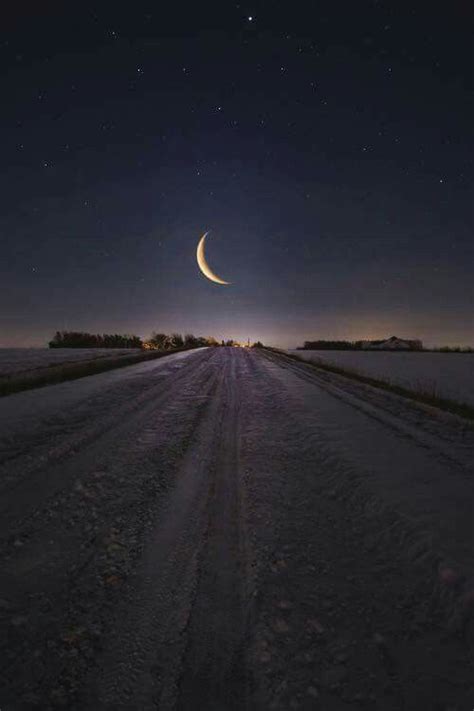 The Moon Is Shining In The Night Sky Over A Snowy Road With Snow On It