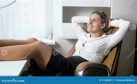 Portrait Of Beautiful Smiling Businesswoman Putting Feet In Pantyhose On Office Desk Stock Image